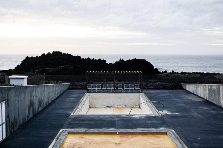 piscina-vacia-sillas-cerca-acantilado-mar
